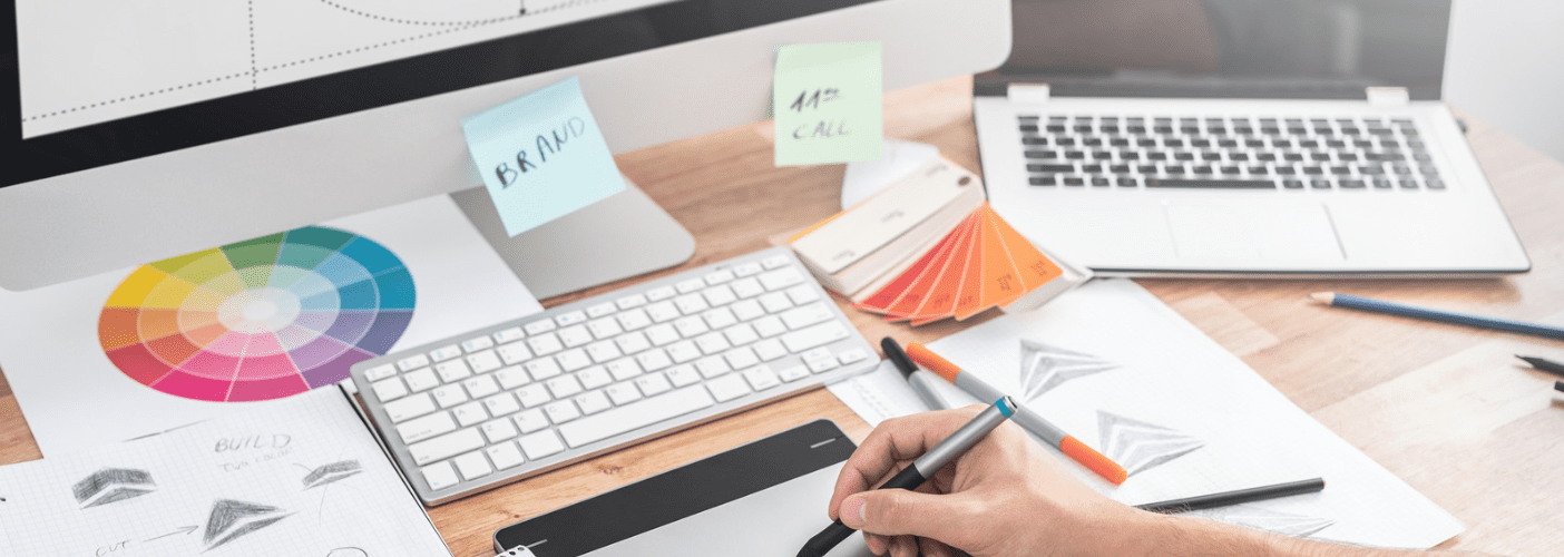 desk with laptop, desktop and notes spread out