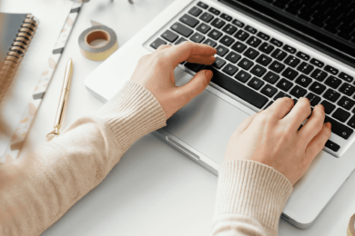 A person is typing on a laptop at a desk.