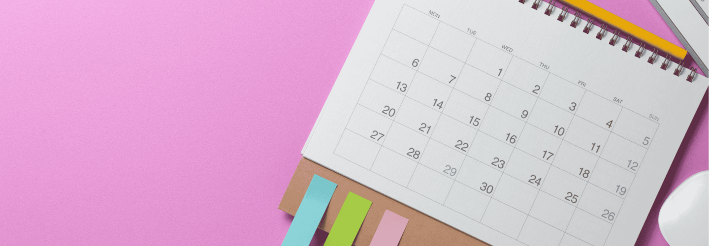 calendar on pink background with keyboard, mouse and sticky notes