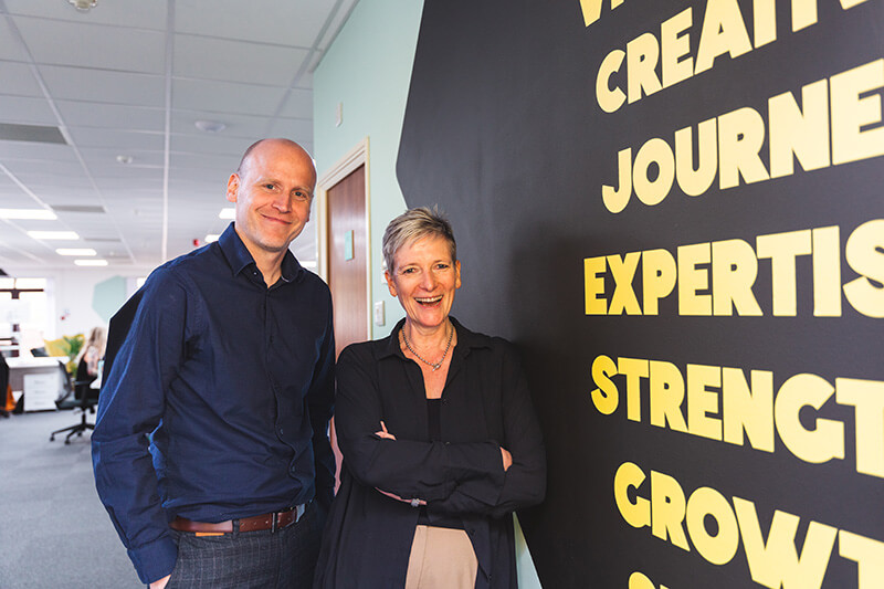 A happy man and woman smiling in the ExtraMile Digital office
