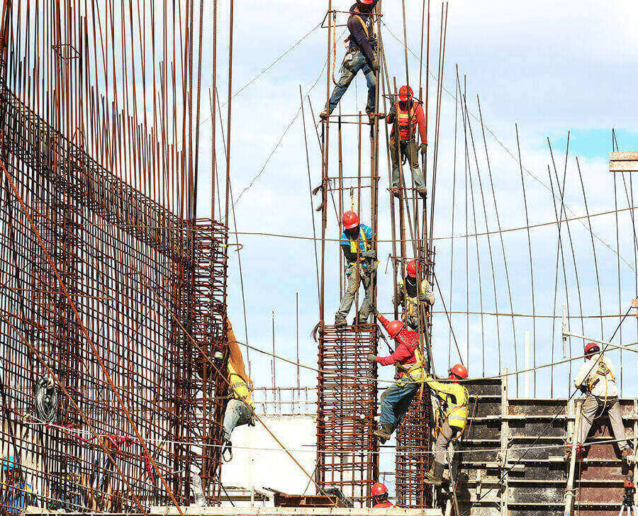Construction workers in safety vests and hard hats, on a construction site building and climbing on scaffolding.