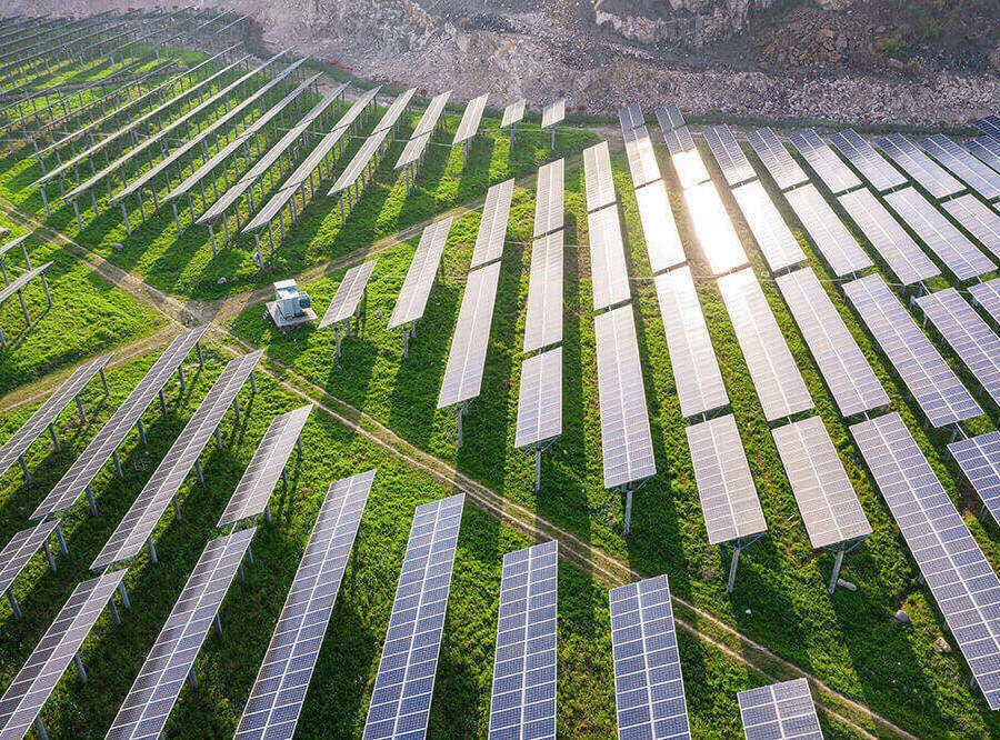 Overhead shot of rows of solar panels in a green, grassy field