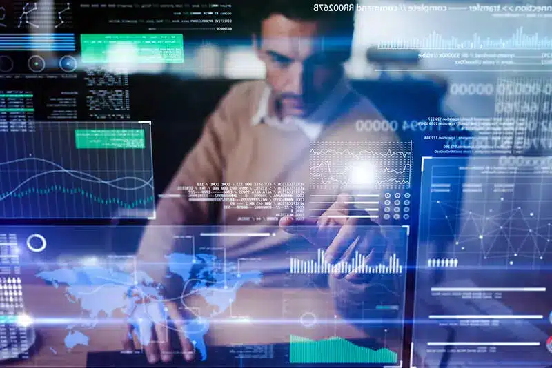 A person interacting with multiple transparent digital screens displaying charts, graphs, and a world map.